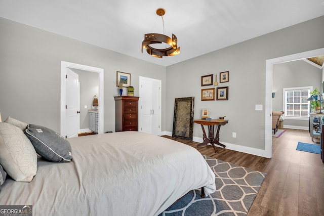 bedroom with ensuite bath, baseboards, and wood finished floors