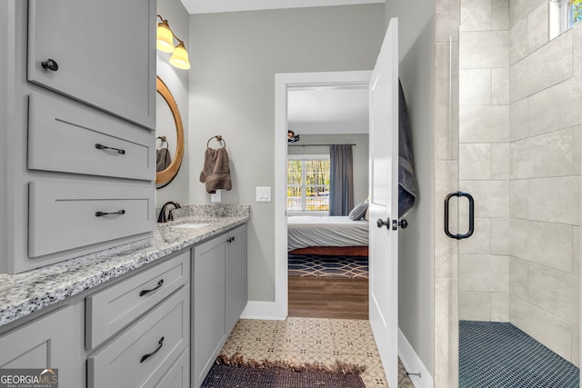 bathroom with baseboards, vanity, a stall shower, tile patterned floors, and ensuite bath