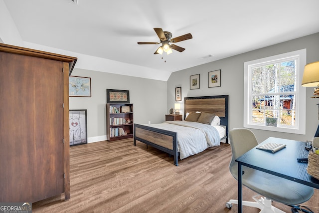 bedroom with lofted ceiling, wood finished floors, visible vents, and baseboards