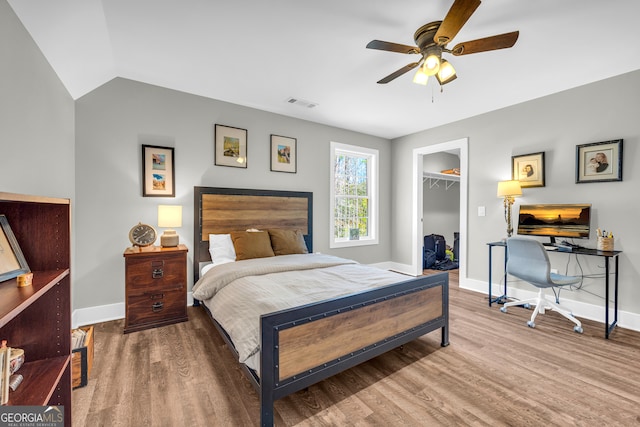 bedroom with visible vents, baseboards, wood finished floors, and a spacious closet