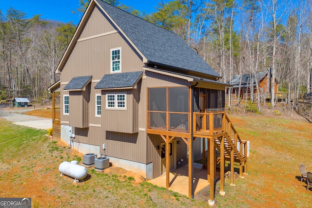 exterior space featuring a patio area, a shingled roof, a yard, and a sunroom