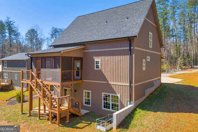 back of house featuring a wooden deck, a lawn, a sunroom, and roof with shingles