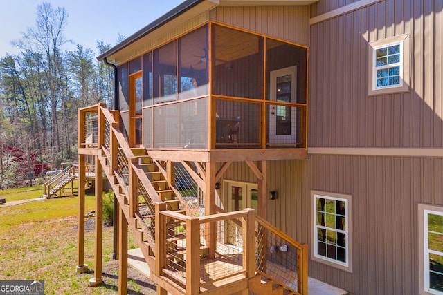 exterior space featuring stairs, a yard, a sunroom, and a wooden deck