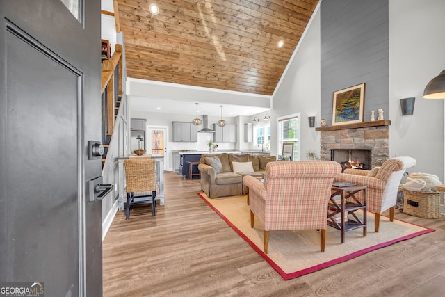 living area featuring wooden ceiling, high vaulted ceiling, light wood-style flooring, and a fireplace