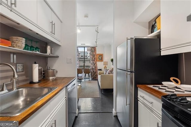 kitchen with open shelves, butcher block counters, and a sink