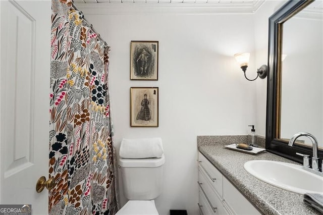 bathroom with toilet, vanity, and crown molding