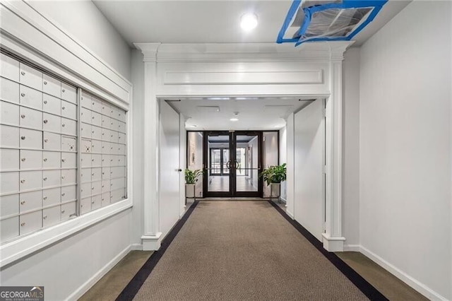 corridor featuring mail area, baseboards, and dark carpet