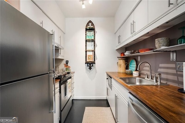 kitchen with butcher block countertops, a sink, open shelves, stainless steel appliances, and white cabinets