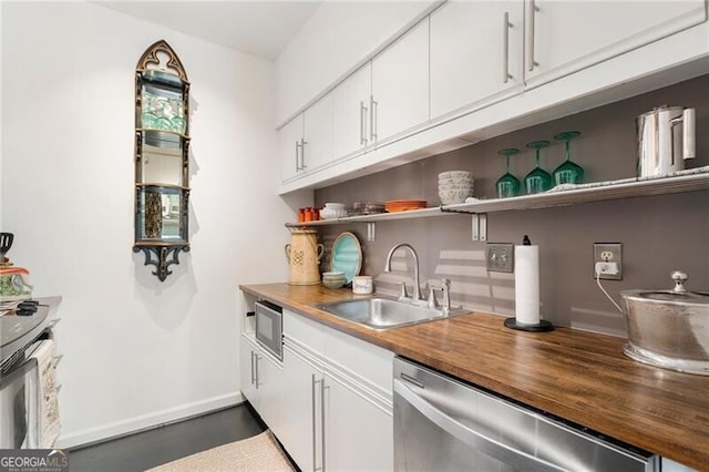 kitchen with a sink, open shelves, butcher block counters, white cabinetry, and stainless steel dishwasher