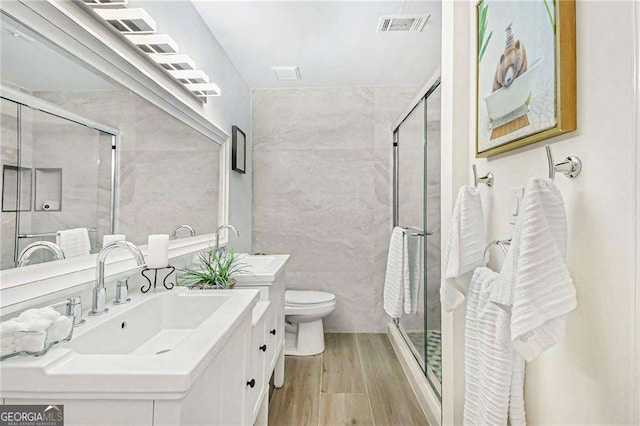 bathroom featuring visible vents, toilet, wood finished floors, and a shower stall