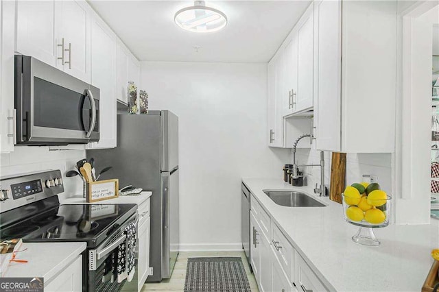 kitchen featuring backsplash, light countertops, appliances with stainless steel finishes, white cabinetry, and a sink