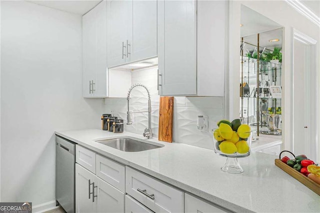 kitchen with light stone counters, white cabinetry, a sink, dishwasher, and tasteful backsplash