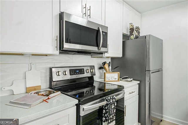 kitchen featuring stainless steel appliances, backsplash, white cabinets, and light countertops