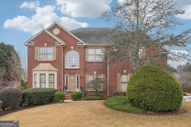 view of front facade featuring brick siding and a front yard