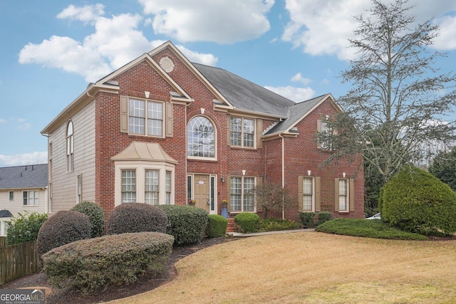 view of front facade with a front yard, fence, and brick siding