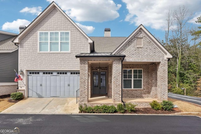 view of front facade featuring driveway, french doors, a garage, brick siding, and a chimney