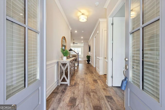 foyer with ornamental molding, wood finished floors, recessed lighting, wainscoting, and a decorative wall