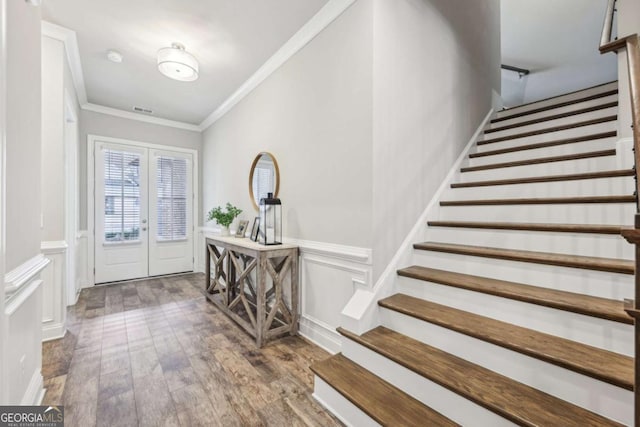 entryway featuring a wainscoted wall, visible vents, wood finished floors, stairway, and crown molding