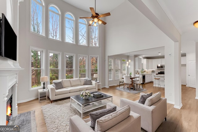 1900 Sanborne Way, Dacula, GA 30019 - living room with a ceiling fan, a fireplace with flush hearth, healthy amount of natural light, a high ceiling, and light wood-style floors