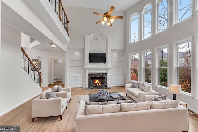 1900 Sanborne Way, Dacula, GA 30019 - living area featuring a high ceiling, stairway, a premium fireplace, ceiling fan, and light wood-style flooring