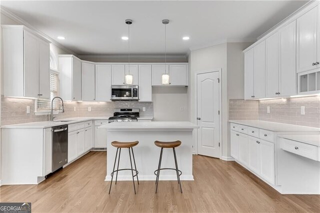 kitchen with crown molding, light wood-type flooring, appliances with stainless steel finishes, white cabinets, and a sink