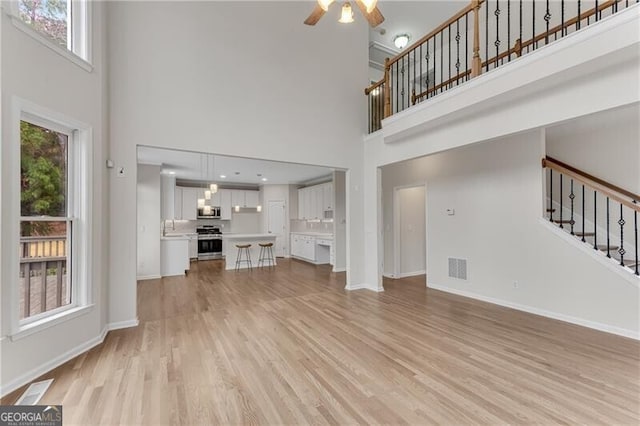 1900 Sanborne Way, Dacula, GA 30019 - unfurnished living room featuring a high ceiling, light wood-type flooring, stairway, plenty of natural light, and a ceiling fan