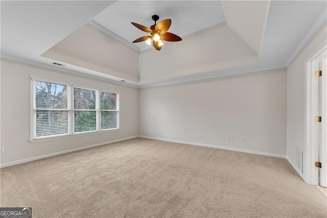 carpeted spare room with a tray ceiling, baseboards, visible vents, and ceiling fan