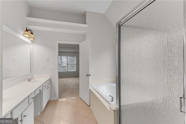 bathroom featuring tile patterned floors, a garden tub, double vanity, and a sink