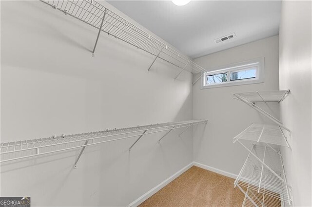 walk in closet with visible vents and light carpet