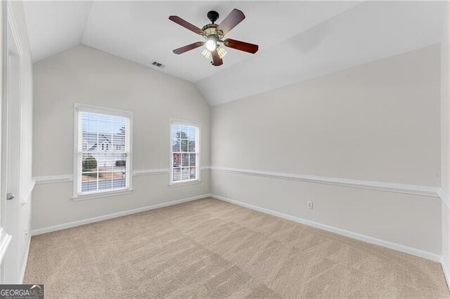 spare room with visible vents, carpet flooring, baseboards, and lofted ceiling