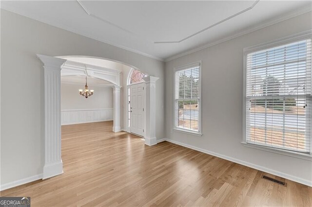 unfurnished dining area with arched walkways, visible vents, an inviting chandelier, and decorative columns