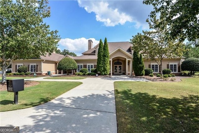 view of front of house featuring a front yard, french doors, and a chimney