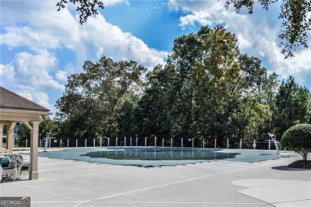 pool with a patio area and fence