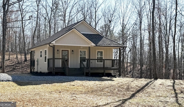 view of front facade with covered porch, board and batten siding, and a shingled roof