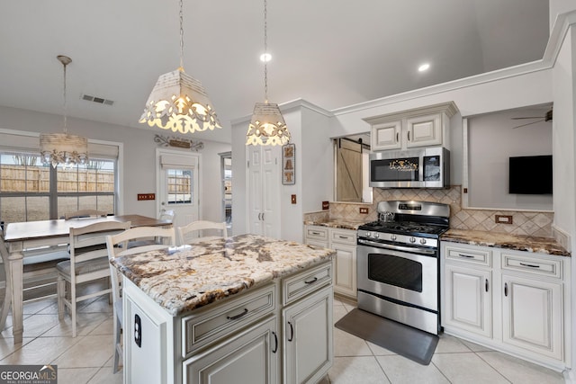 kitchen with visible vents, light stone countertops, a barn door, decorative backsplash, and appliances with stainless steel finishes