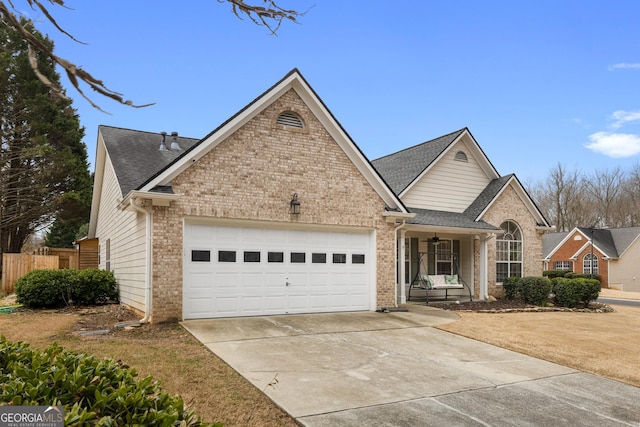 traditional-style house with brick siding, fence, roof with shingles, a garage, and driveway