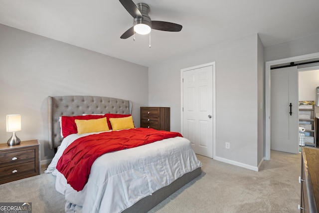 bedroom featuring light colored carpet, baseboards, a barn door, and ceiling fan