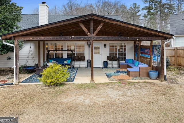 rear view of house featuring an outdoor living space, a patio, roof with shingles, and fence