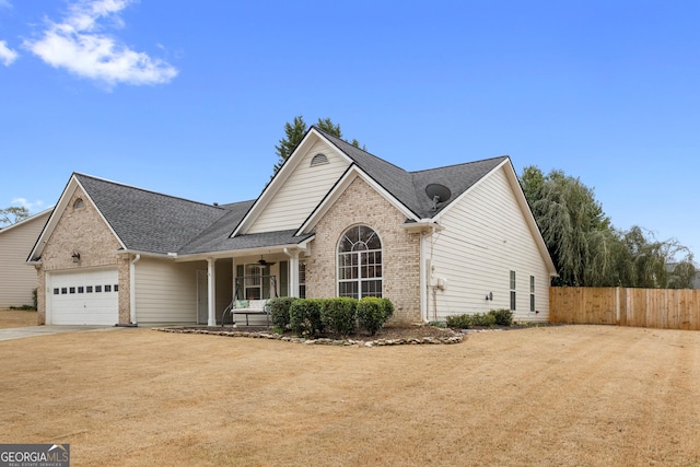 traditional home featuring a ceiling fan, fence, concrete driveway, an attached garage, and brick siding