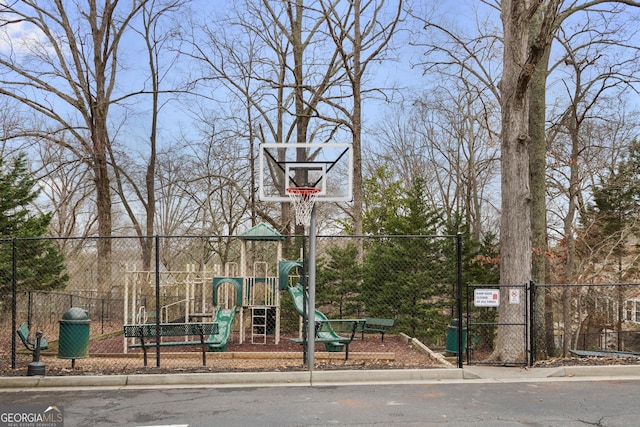 view of basketball court featuring playground community and fence