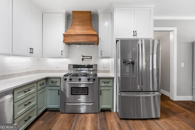 kitchen with white cabinetry, dark wood finished floors, custom range hood, appliances with stainless steel finishes, and green cabinets