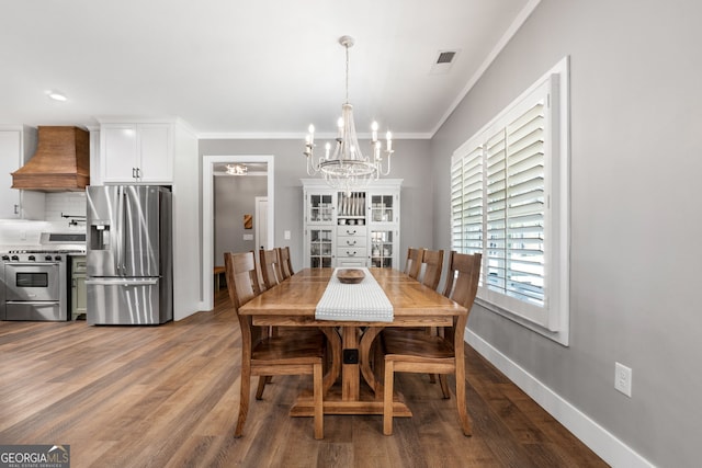 dining space featuring visible vents, crown molding, baseboards, an inviting chandelier, and wood finished floors