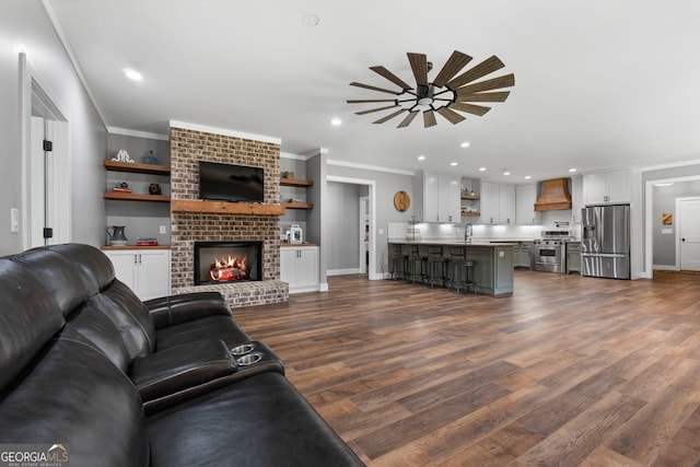 living room with recessed lighting, a fireplace, dark wood-type flooring, and crown molding