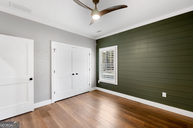 unfurnished bedroom with wood finished floors, visible vents, and baseboards