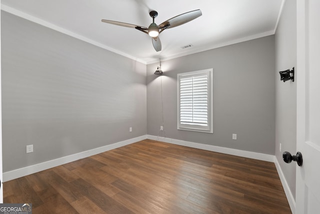 empty room featuring baseboards, wood finished floors, visible vents, and ornamental molding