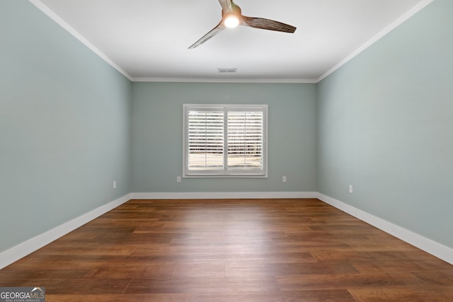 empty room with wood finished floors, baseboards, and ornamental molding