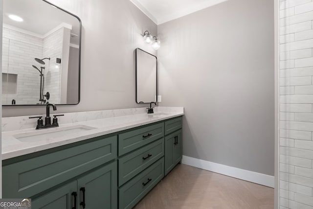 bathroom with a sink, baseboards, double vanity, and a tile shower