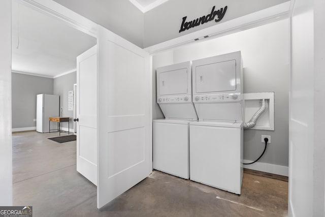 laundry area with stacked washer / drying machine, baseboards, laundry area, and crown molding