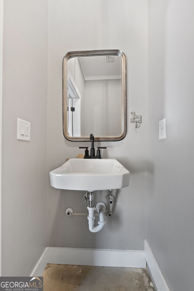 bathroom featuring a sink, baseboards, and concrete floors