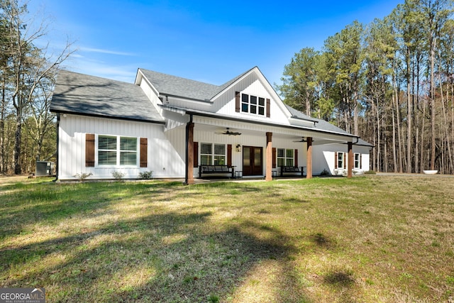 modern farmhouse style home with a front lawn, a ceiling fan, french doors, and roof with shingles